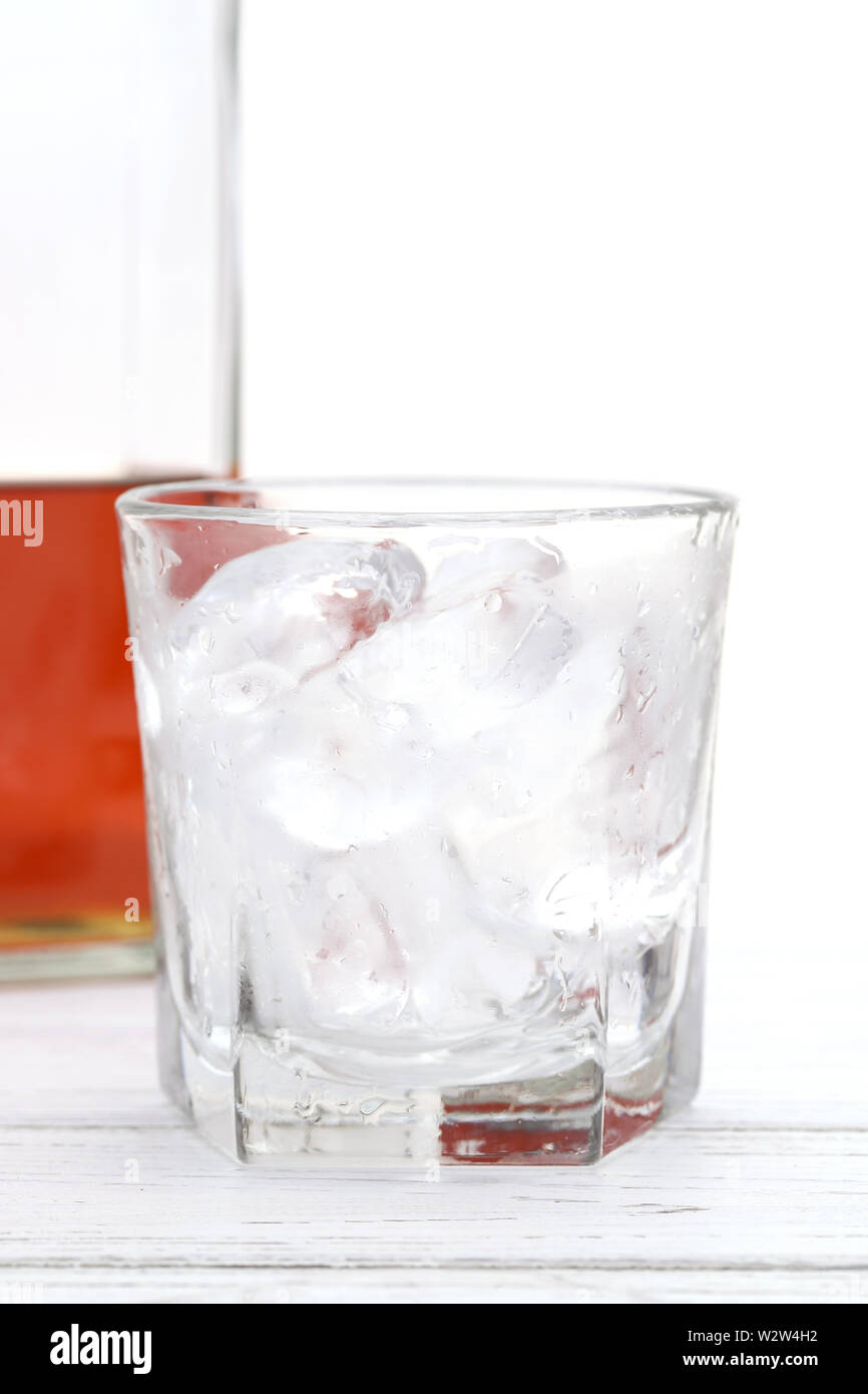 Bicchiere di vetro e una bottiglia di whiskey su sfondo bianco Foto Stock