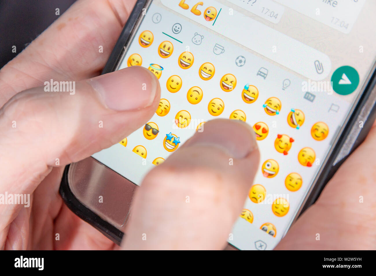Una persona la digitazione di caratteri Emoji in una chat app Foto Stock