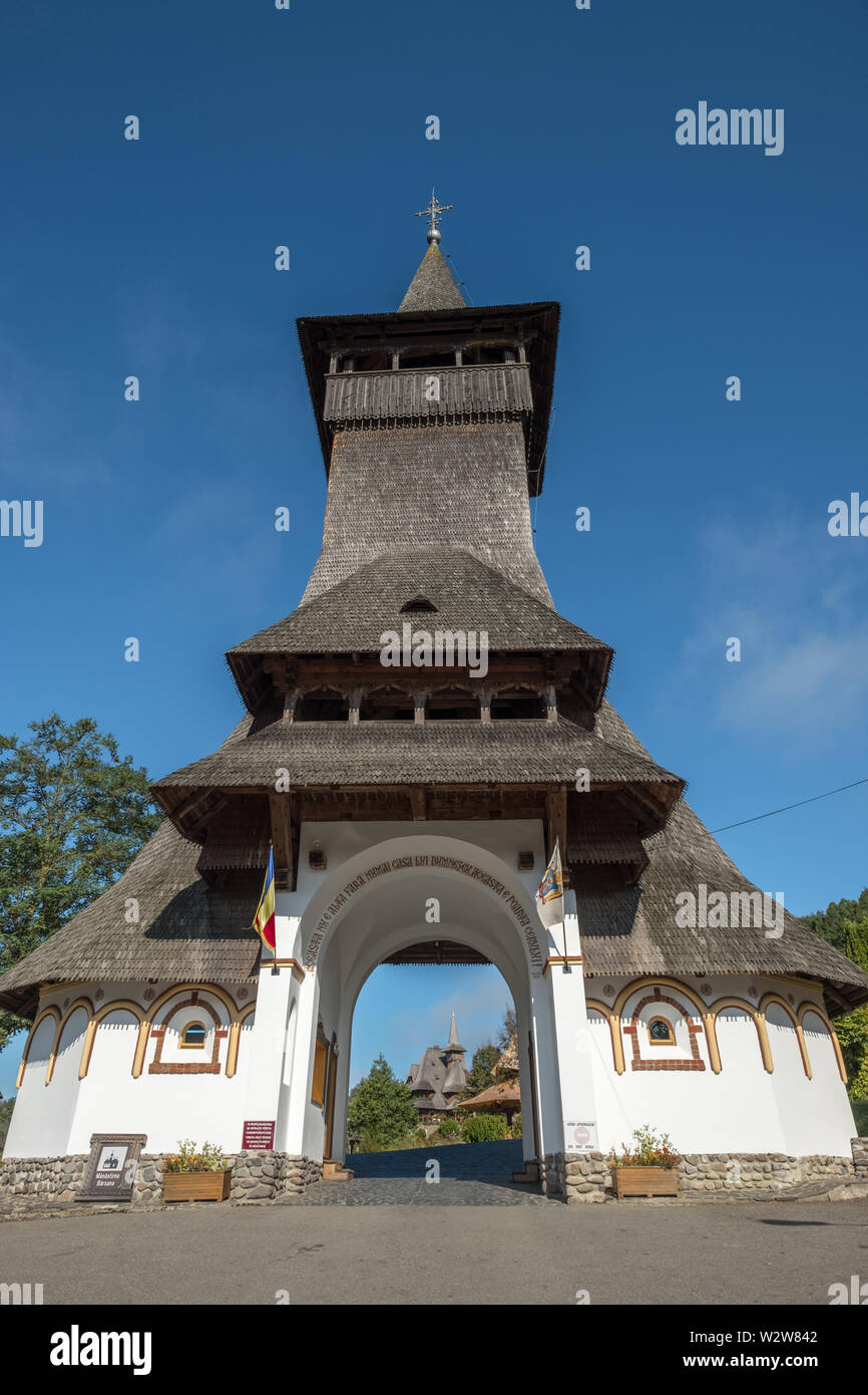 Guardando attraverso unico ingresso con molto alta in legno con tetto di scandole torre per motivi di Barsana Monastero, Maramures, Romaina Foto Stock
