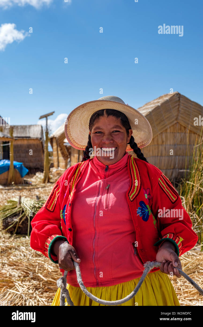 Ritratto di una sorridente donna indigena Uru che accoglie i visitatori di un'isola galleggiante con canne totora, isole galleggianti di Uros, lago Titicaca, Uros, P. Foto Stock
