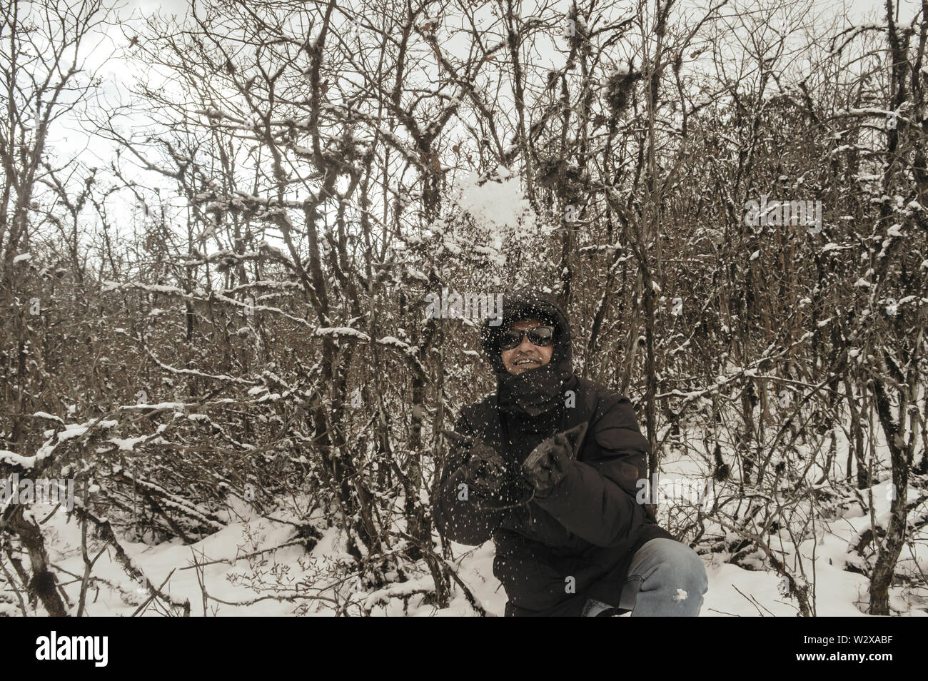 Sorridendo felice gioiosa Ritratto di un uomo che indossa un maglione nero giacca godendo prima neve giocando e lanciando palle di neve in aria. Godetevi nevicava giorno vie Foto Stock