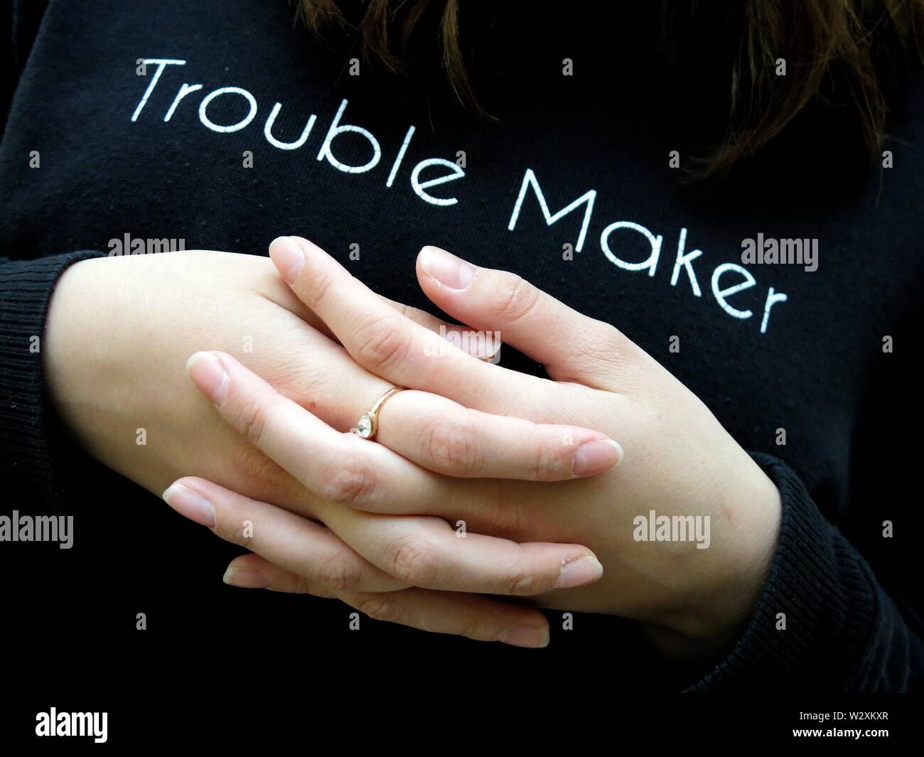 Ragazza adolescente con mani incrociate indossando "trouble maker" ponticello. (Giustapposizione di sentimenti durante l adolescenza). Foto Stock