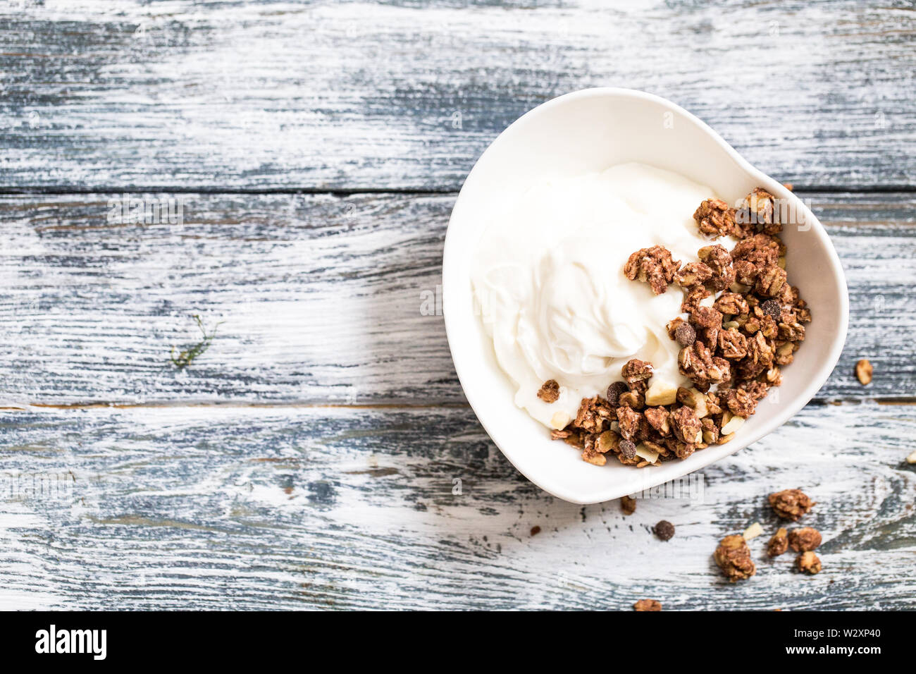 Lo yogurt greco e granola in una ciotola bianco su uno sfondo di legno. Foto Stock