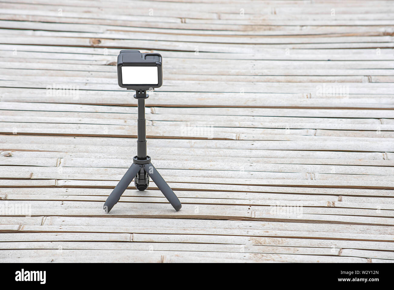 Fotocamera e video con un piccolo supporto nero su un pavimento in bambù. Foto Stock