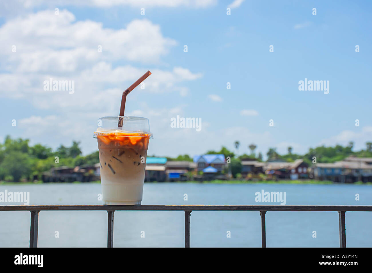 Bicchiere di caffè freddo sul balcone in ferro viste di sfondo del fiume e la casa. Foto Stock