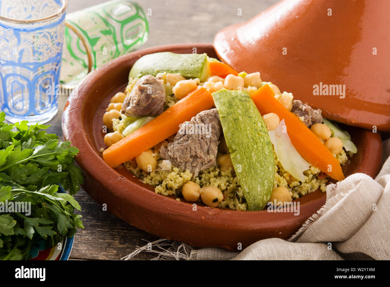 Tajine tradizionale con verdure, i ceci, la carne e il couscous sulla tavola di legno Foto Stock