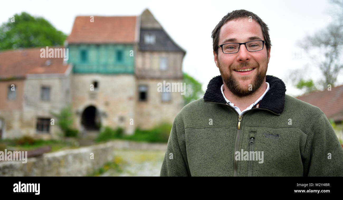 26 aprile 2019, il Land Turingia, Wachstedt: Christoph Weidner, signore del castello, ambientale pedagogo e automotive tecnico meccatronica, sorge di fronte al 800-anno-vecchio castello Gleichenstein nell'Eichsfeld nel nord della Turingia. Il 35-anno-vecchio figlio di un sacerdote che affonda le sue radici nella parte orientale della Turingia ha acquisito il male il castello danneggiato lo scorso anno al fine di salvare e rilanciare. È la pianificazione di un posto per la celebrazione e per la canapa manifattura di schiuma. Un piccolo museo è anche quello di essere costruito. Foto: Martin Schutt/dpa-Zentralbild/dpa Foto Stock