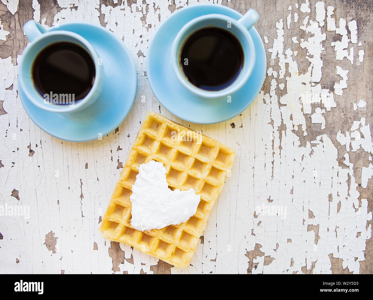 I waffle belgi e due tazze di caffè su un vecchio tavolo in legno Foto Stock