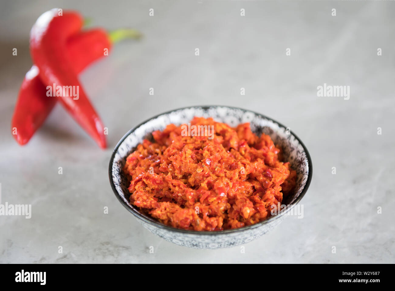 Magrebino tradizionale peperoncino piccante salsa Harissa su un marmo grigio Sfondo. Cucina Araba. Adjika di salsa al peperoncino piccante. Peperoncini calabrese con o Foto Stock