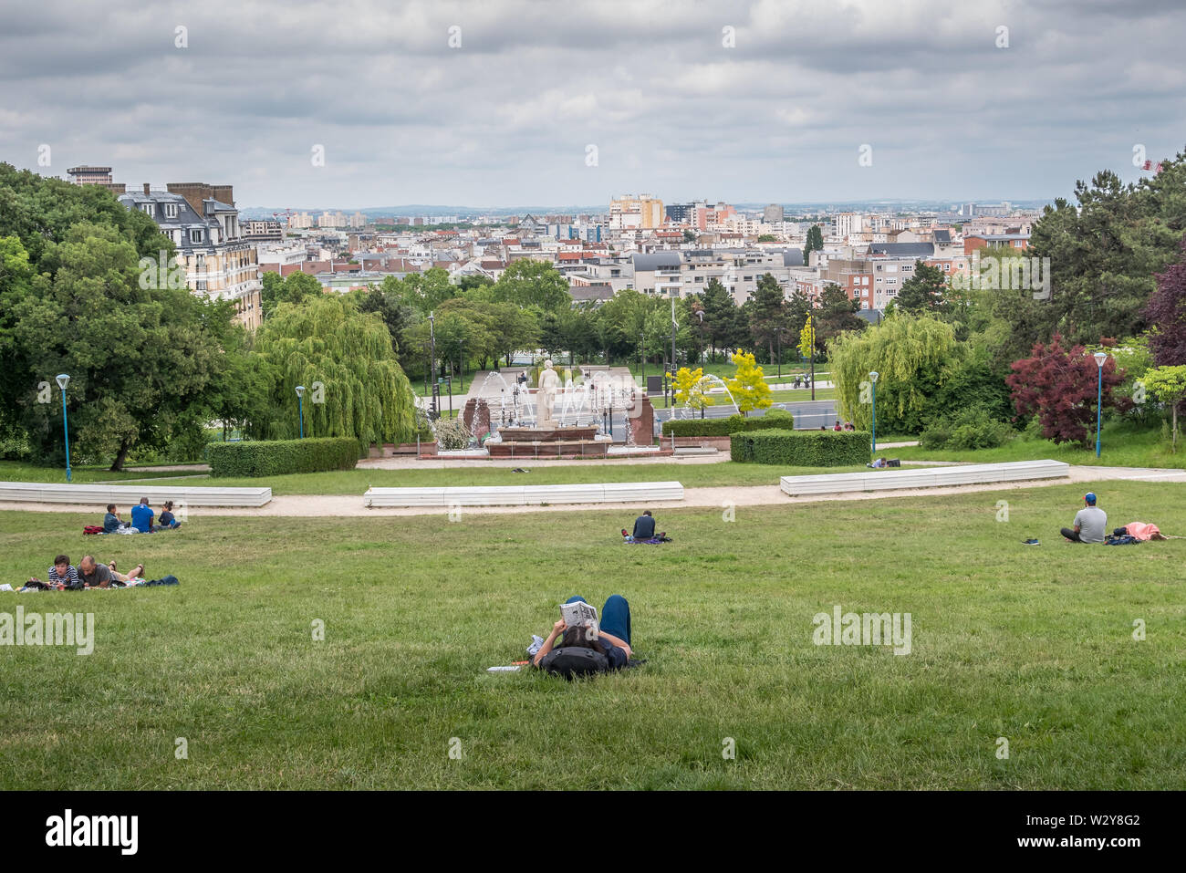 Parigi, Francia - 26 Maggio 2019: Butte du Chapeau Rouge park a Parigi con la gente il relax e la lettura sull'erba Foto Stock