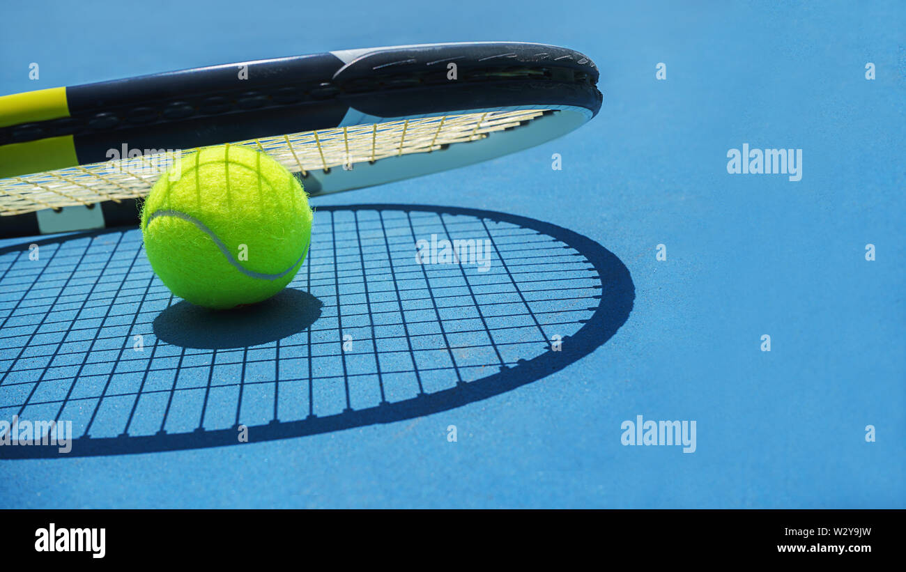 Estate sport concetto con palla da tennis e racket sul blu del disco di un campo da tennis. Foto Stock