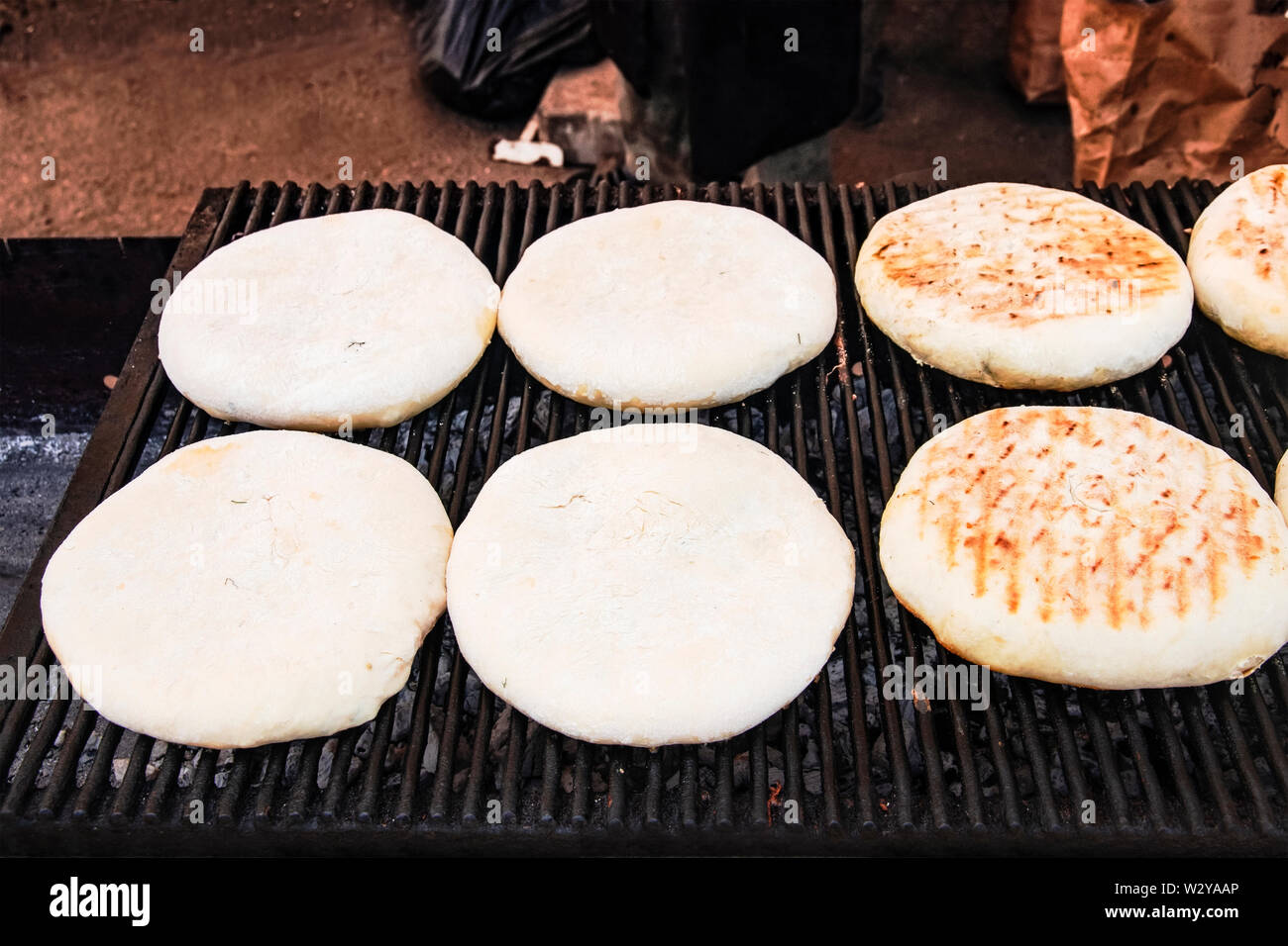 Round, gustoso, lussureggianti tortillas artigianali fatti da farina di grano sono cotte sulla griglia sui carboni ardenti. Il pane è tostato su un barbecue esterno per c Foto Stock