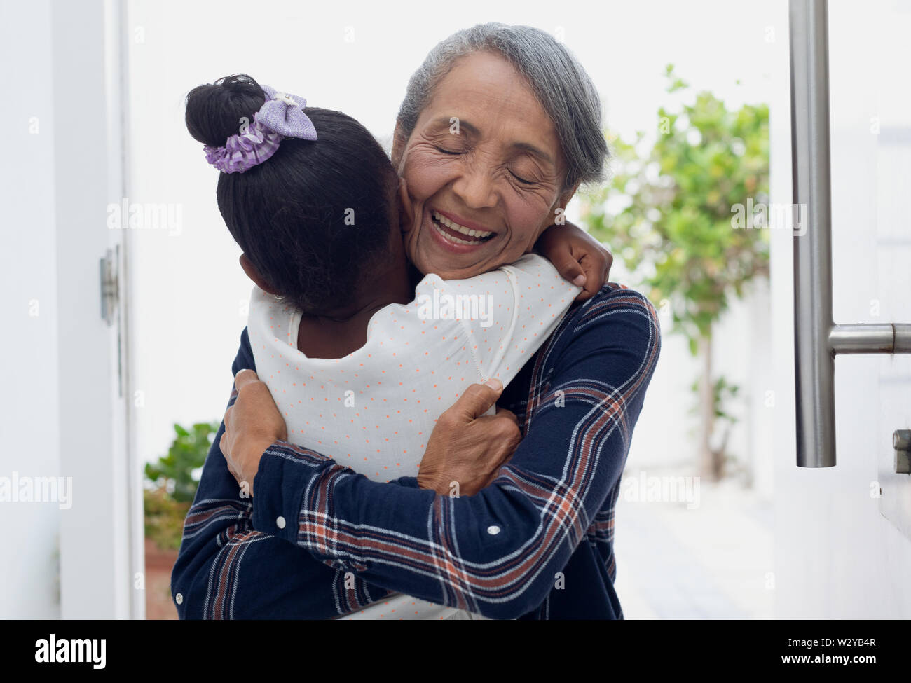 Ragazza abbracciando la nonna mediante la porta Foto Stock