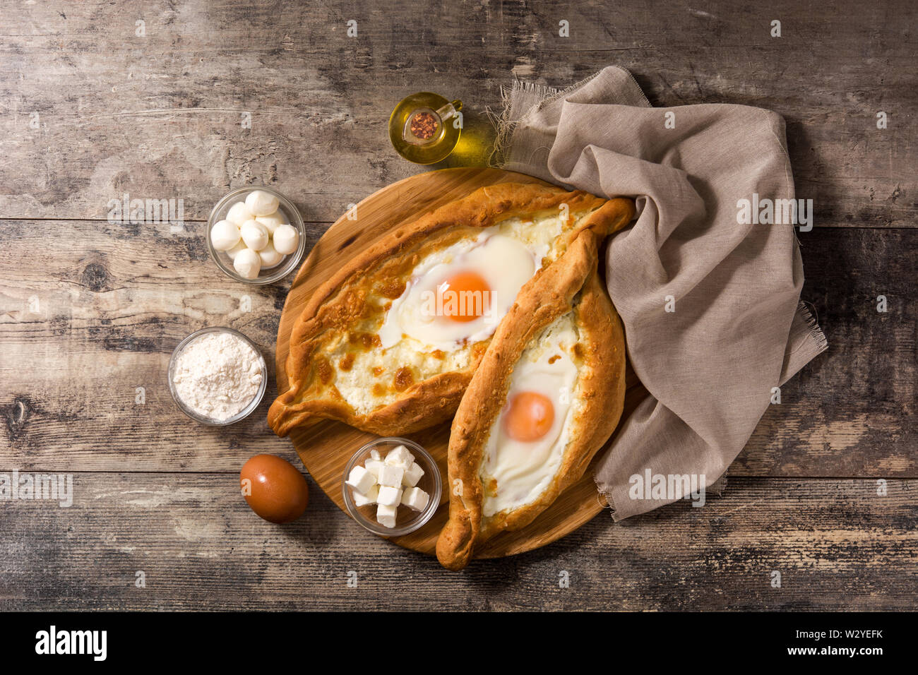 Tradizionale georgiano Adjarian khachapuri con formaggio e uova su un tavolo di legno. Vista superiore Foto Stock