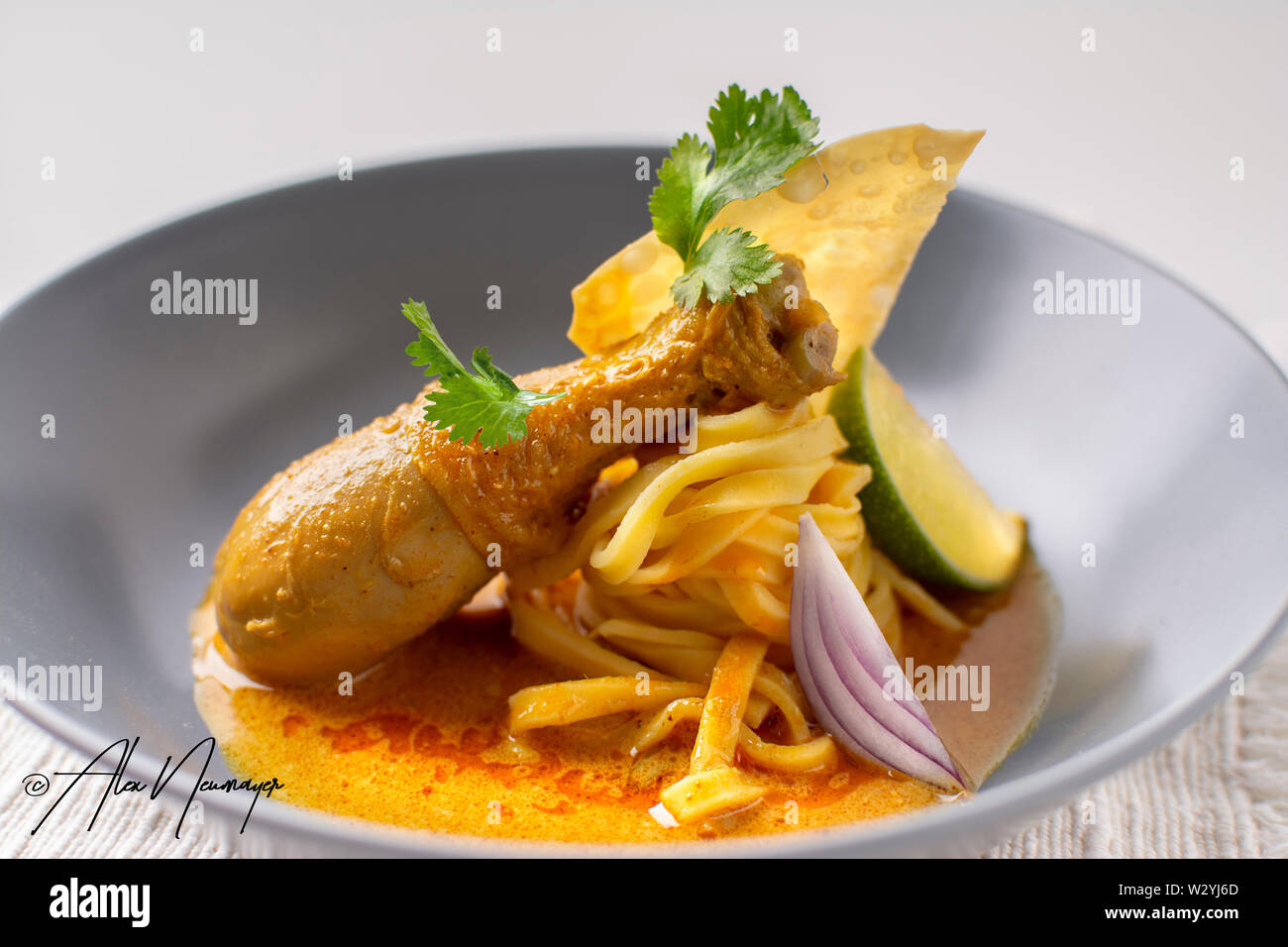 Thai giallo bacchette di pollo al curry con uova fresche tagliatelle , calce, coriandolo e croccante frittura di noodle all'uovo in un piatto placcato Foto Stock