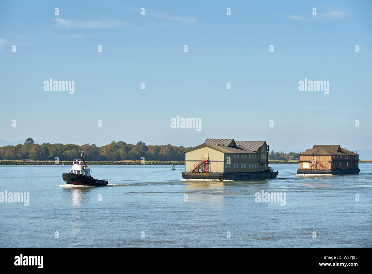 Rimorchiatore a traino e casoni da pesca. Un rimorchiatore di matasse di logge fishcamp alla loro destinazione remota sulla costa BC Foto Stock