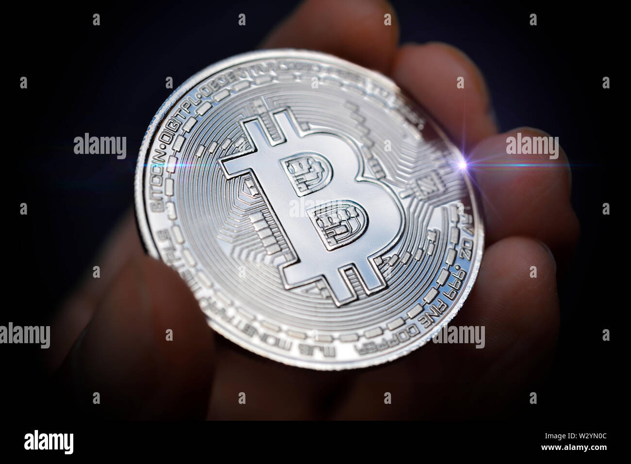 Dito holding Bitcoin coin, moneta virtuale Foto Stock