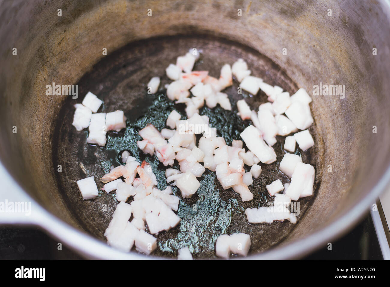 Grasso per friggere la coda in un paiolo di rame sul fornello. Il riscaldamento del lardo in padella. Foto Stock
