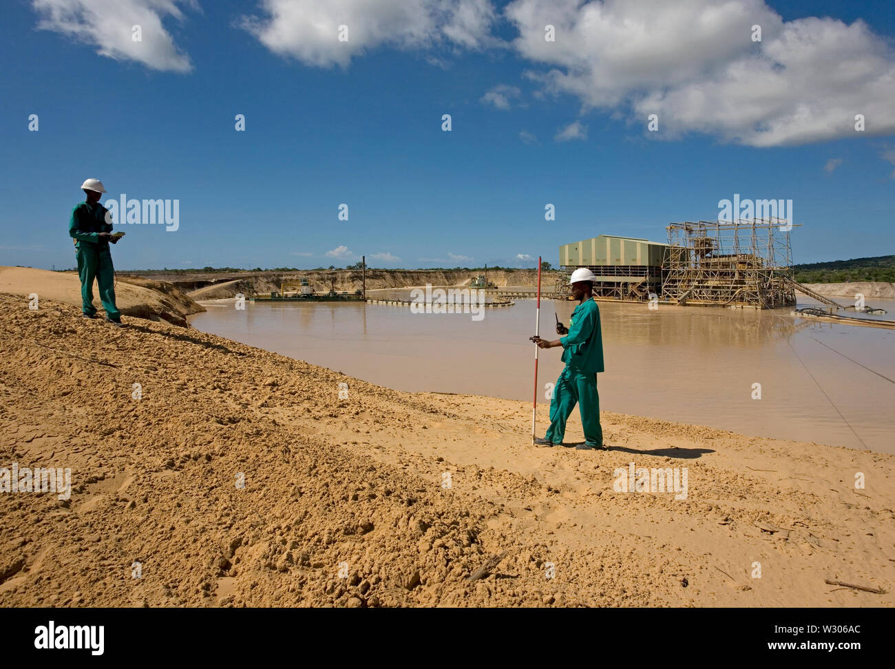 Gestione e trasporto di sabbie minerali di titanio nel sito minerario. Estrazione mineraria utilizzando dredges che pompano sabbia da stagni e geometri d'acqua che misurano le altezze delle dune. Foto Stock