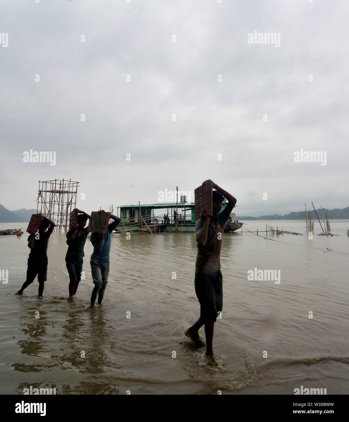 (190711) -- Assam, luglio 11, 2019 (Xinhua) -- Le persone cambino le loro proprietà in allagato fiume Brahmaputra a Guwahati, capitale di Assam, in India, 11 luglio, 2019. Inondazioni da piogge monsoniche nel nord-est dello stato indiano di Assam hanno ucciso tre persone e fregata più di 400.000, funzionari ha detto giovedì. 'Un totale di tre persone di cui due in flood incidenti correlati ed uno in frana sono stati uccisi in Assam finora", un stato di Assam Disaster Management Authority (ASDMA) funzionario detto. (Str/Xinhua) Foto Stock