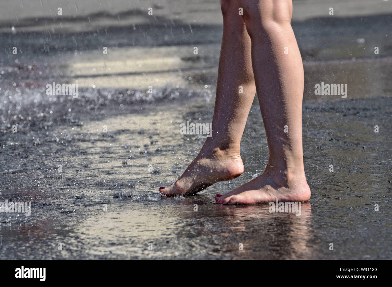 Camminare a piedi nudi sotto la pioggia attraverso le pozzanghere.It è piacevole e salutare. Foto Stock