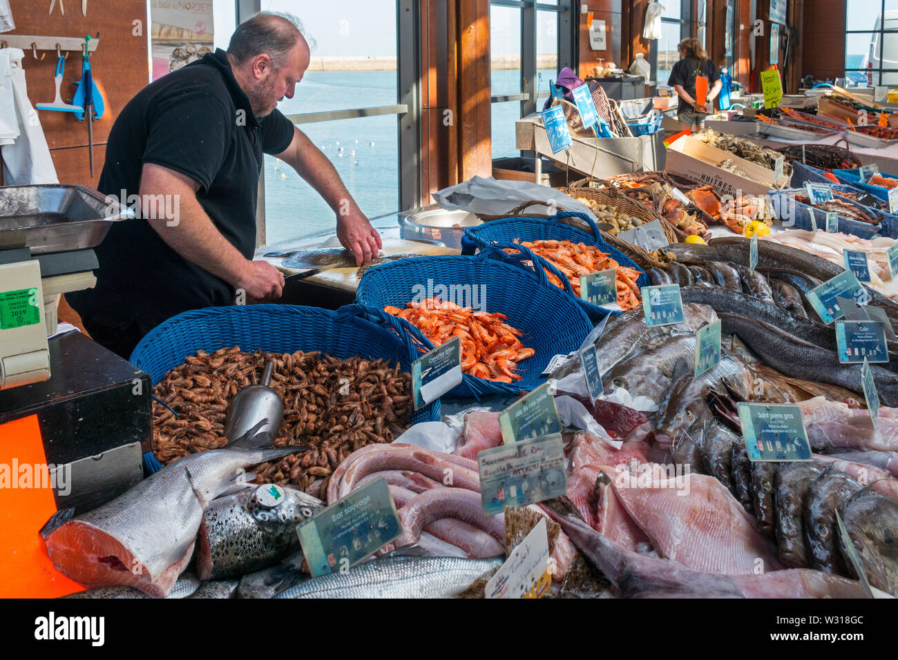 Contatore con pesce fresco e gamberetti sul display al coperto Mercato del pesce al porto a località balneare di Port-en-Bessin, Calvados, Normandia, Francia Foto Stock