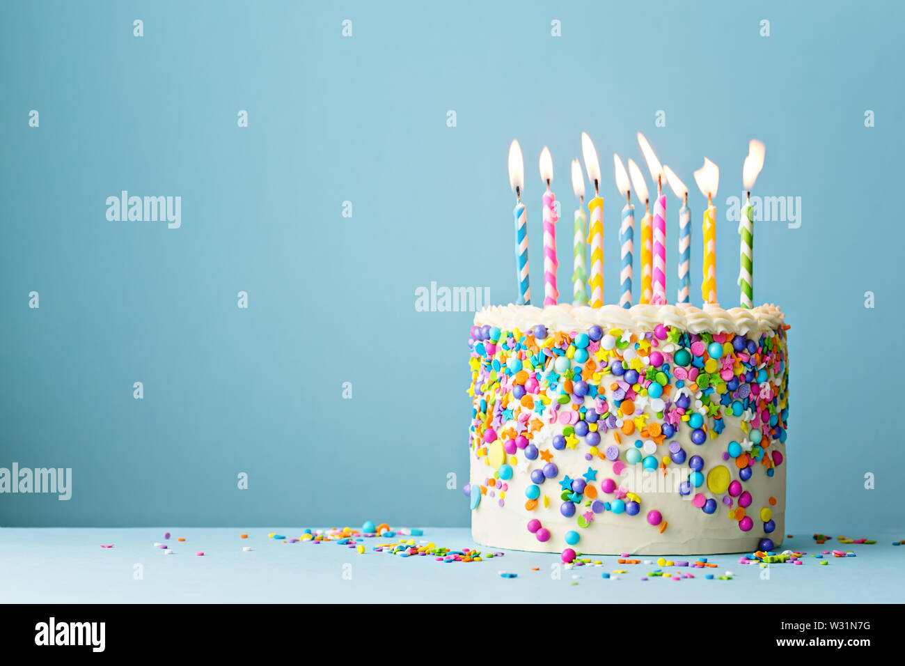 Colorate torta di compleanno con un pizzico e dieci candeline su uno sfondo blu con copyspace Foto Stock