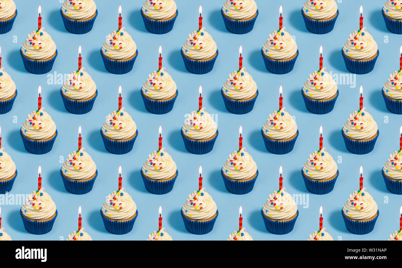 Modello senza cuciture con tortine di compleanno e candele su uno sfondo blu Foto Stock