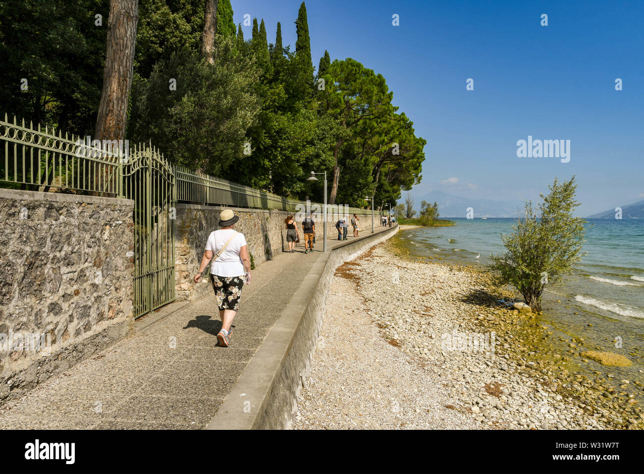 SIRMIONE SUL LAGO DI GARDA, Italia - Settembre 2018: persona che cammina su un percorso attorno al bordo del comune di Sirmione sul Lago di Garda. Foto Stock