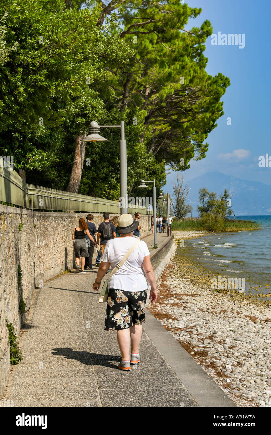 SIRMIONE SUL LAGO DI GARDA, Italia - Settembre 2018: persona che cammina su un percorso attorno al bordo del comune di Sirmione sul Lago di Garda. Foto Stock