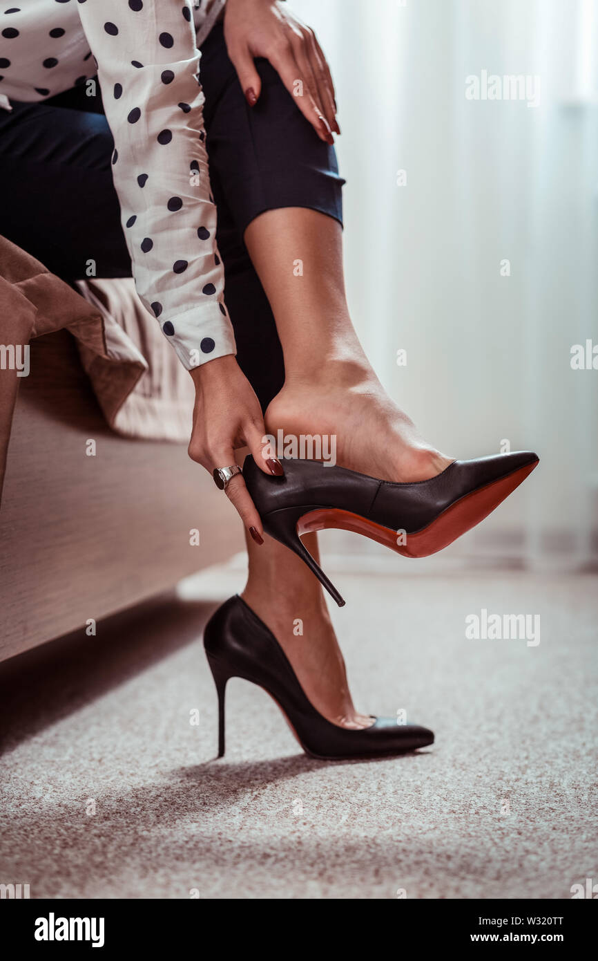 Stanco attraente lady prendendo il largo nero tacchi alti dopo una lunga giornata di lavoro Foto Stock