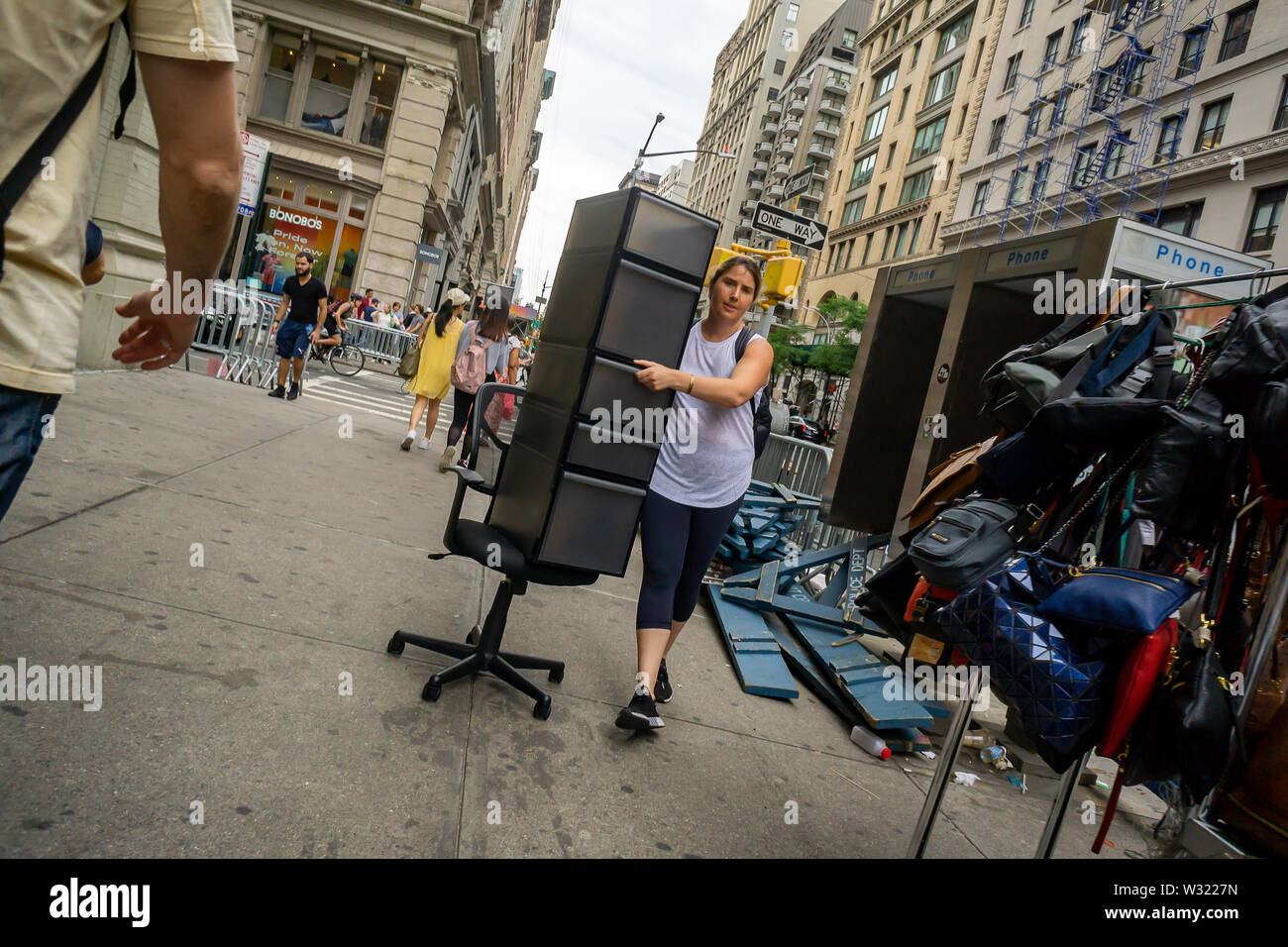 Una donna schleps una unità di storage su una sedia per ufficio come un ripiego dolly nel quartiere Flatiron di New York martedì 2 luglio 2, 2019. (© Richard B. Levine) Foto Stock
