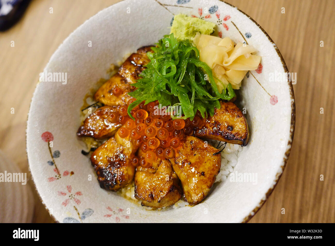 Grigliata di foie gras guarnita con uova di salmone, zenzero sott'aceto e cipolline sulla sommità del caldo cotto a vapore il riso è uno dei piatti in Gojuu Sushi. Foto Stock