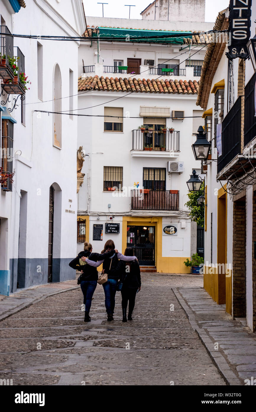 Tre amici percorrendo a piedi una tipica cittadina spagnola strada residenziale di Cordoba e un grande esempio del pueblo blanco (villaggio bianco) aree di EUN Foto Stock