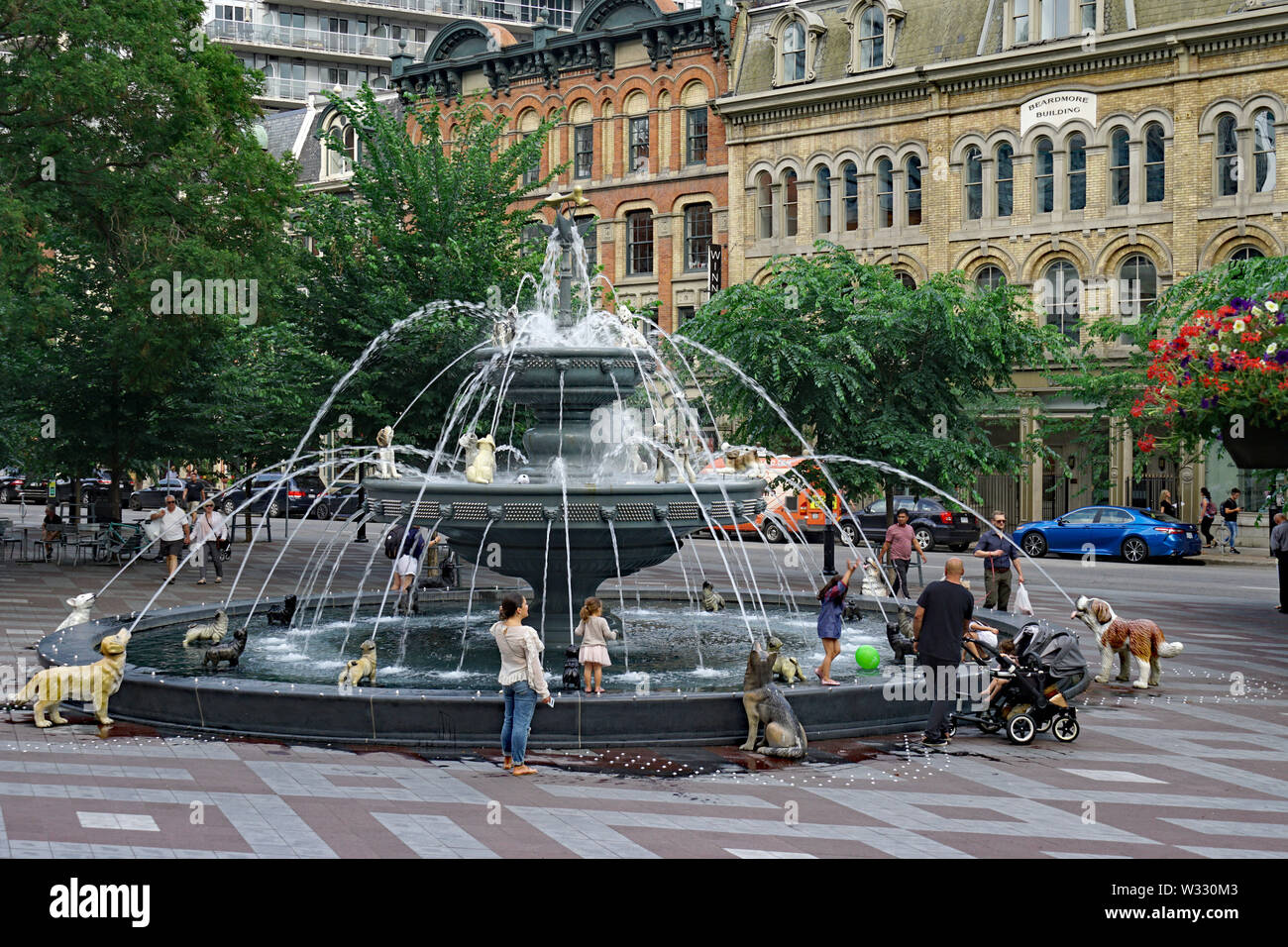 TORONTO - Luglio 2019: il cane Fontana nel parco Berczy vicino a Toronto il distretto finanziario, con 1870 ghisa edifici in background. Foto Stock