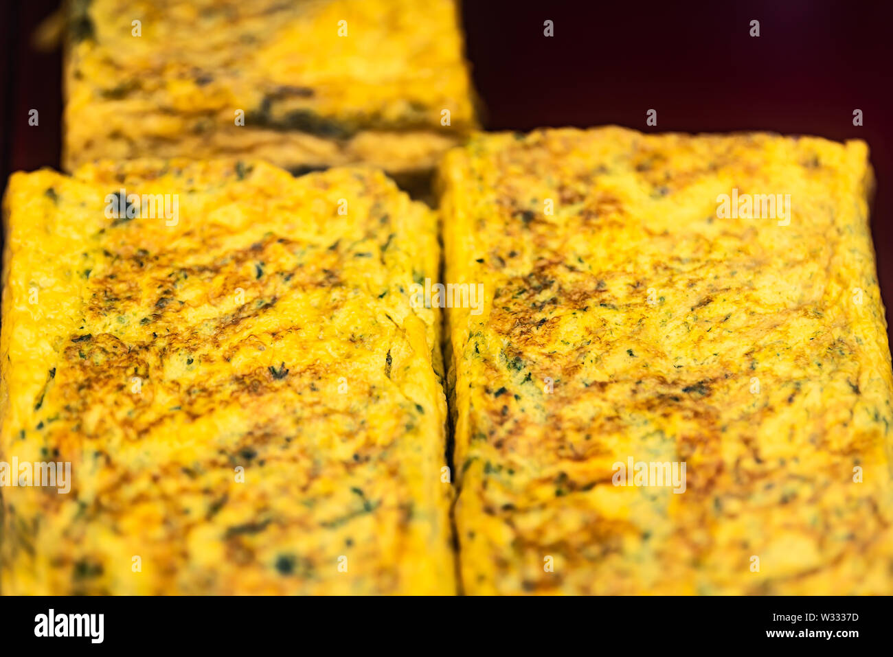 Macro closeup di tamagoyaki giapponese uova frittata arrotolata su retail display in Ginza del pesce di Tsukiji street mercato esterno con nessuno Foto Stock