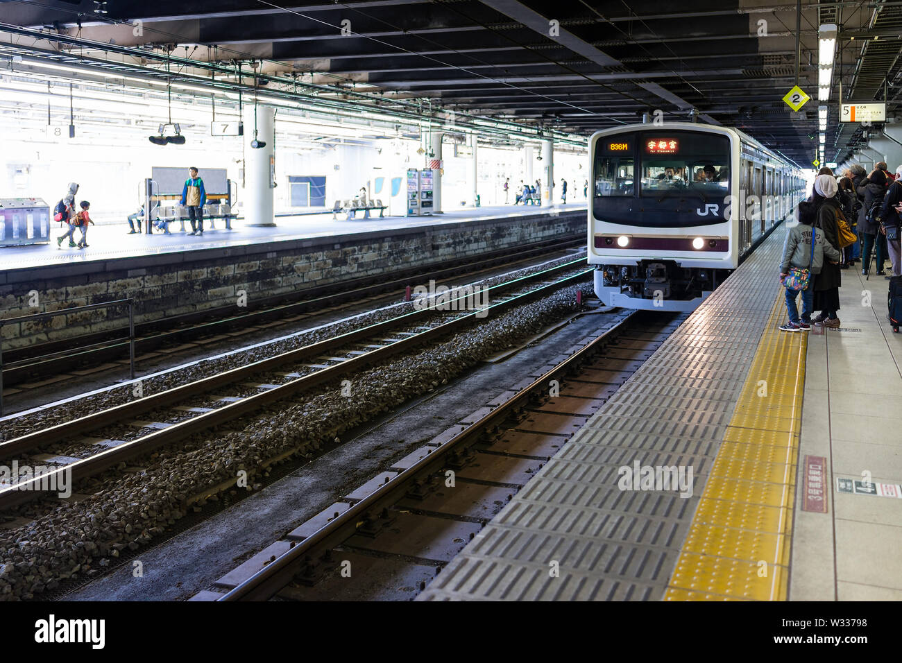 Utsunomiya, Giappone - Aprile 4, 2019: Stazione ferroviaria piattaforma linea locale a Nikko segno con molte persone in piedi sulla piattaforma e segno JR Foto Stock