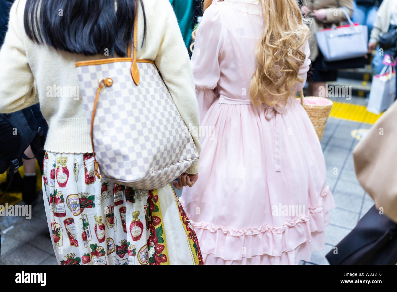 Tokyo, Giappone - Aprile 4, 2019: indietro di due giovani donne ragazze vestite in cosplay bambole, abito rosa all'interno della trafficata Shinjuku stazione ferroviaria terminale con p Foto Stock