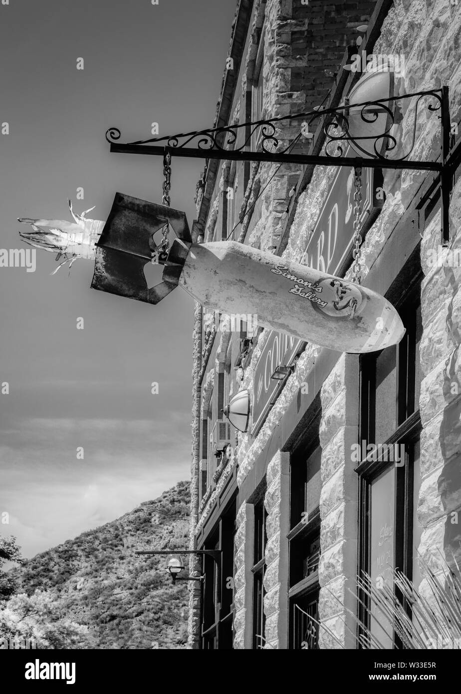 Un vecchio arrugginito WWII bomba aerea convertito ad arte con pinup ragazza la decalcomania è appeso un cartello in metallo di overhead del frame di ingresso vicino al cortile, Bisbee, AZ Foto Stock