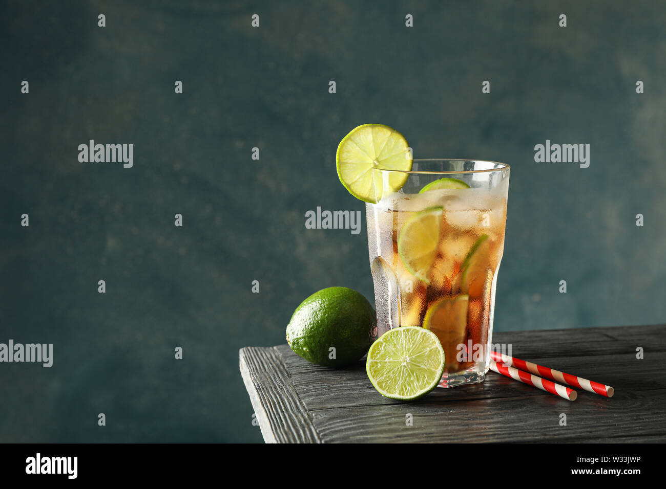 Vetro a freddo cola con agrumi e ghiaccio sul tavolo di legno contro uno sfondo scuro Foto Stock