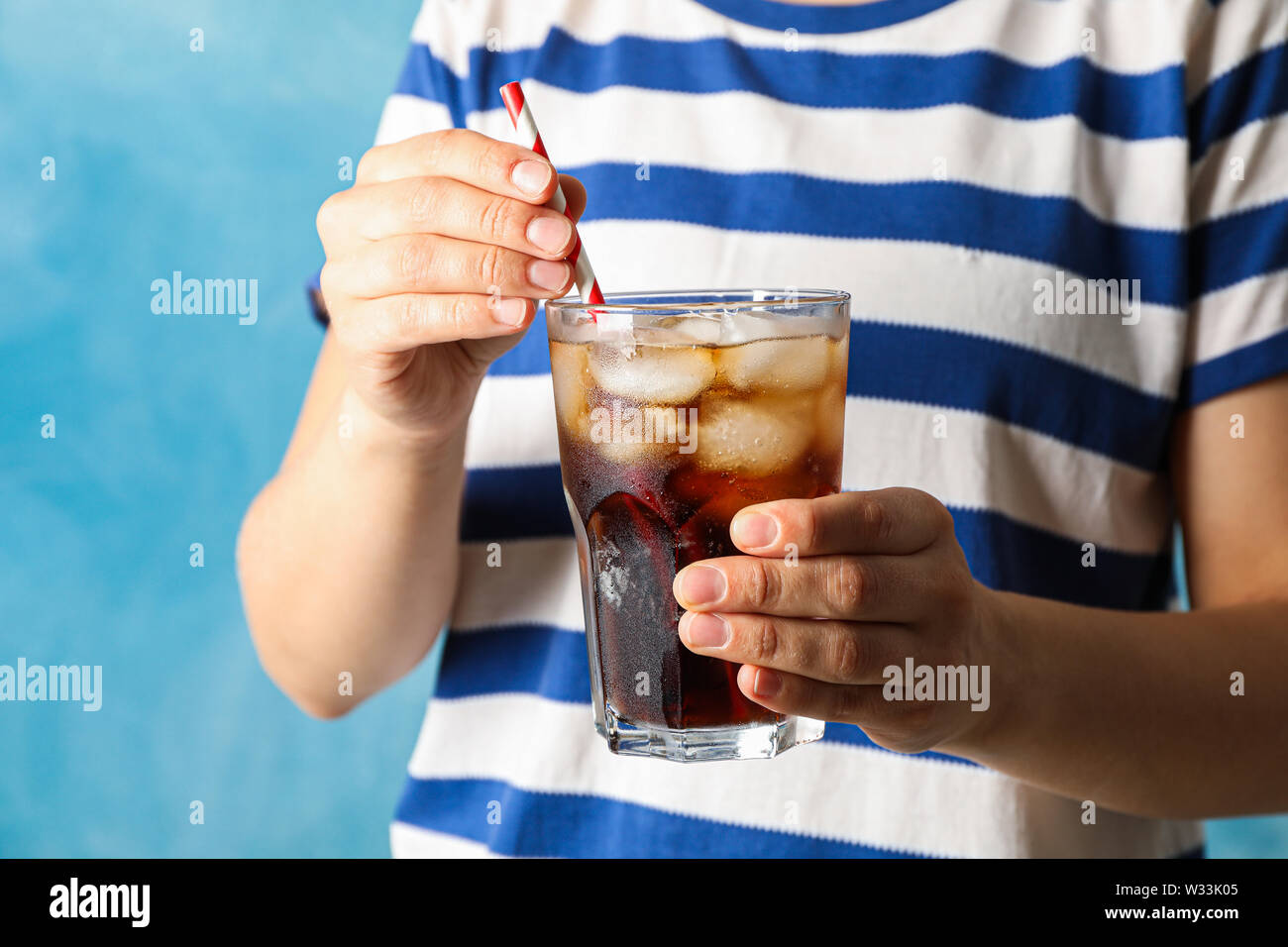 Mani femminili con in mano un bicchiere con cola e del tubicino Foto Stock
