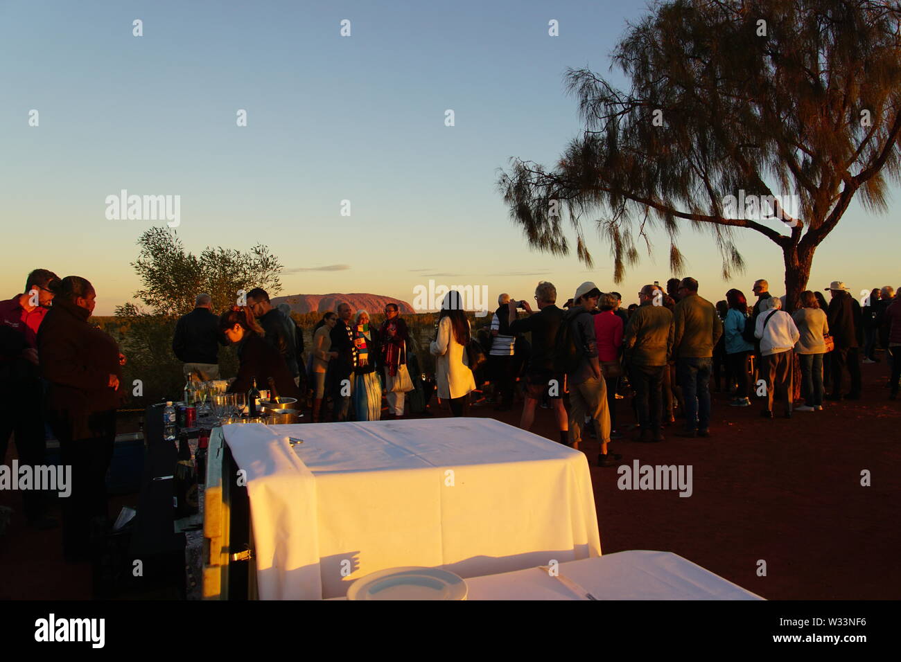 Persone di assaporare un tramonto di Uluru con bevande e tartine Foto Stock