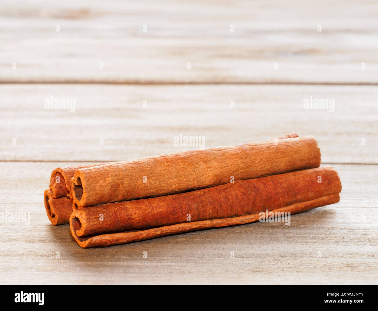 La cannella (Cinnamomum verum) su un marrone di sfondo di legno Foto Stock