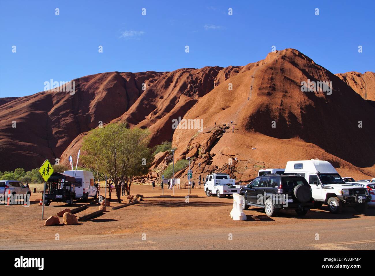 Mala Parcheggio auto e persone a scalare Uluru Foto Stock