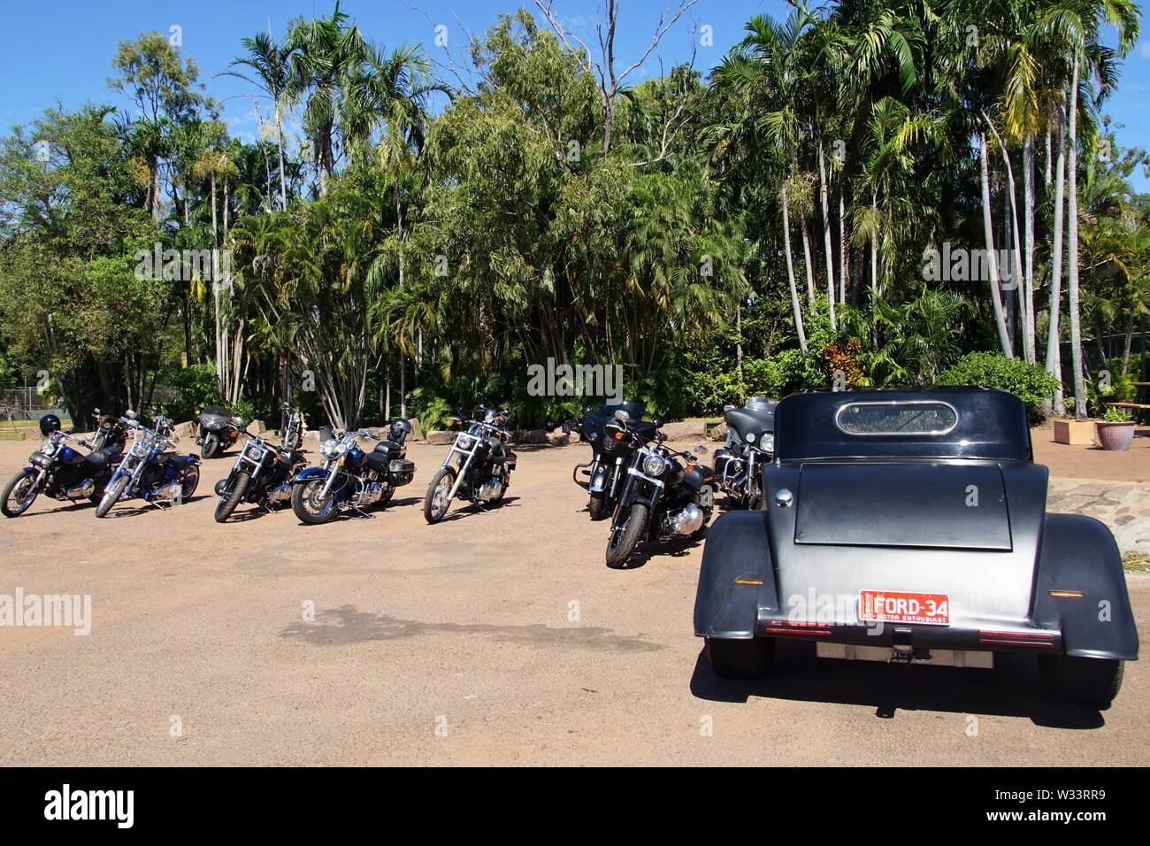 Vintage auto e moto parcheggiata di fronte un boschetto di palme al di fuori del parco Corroboree Taverna Foto Stock