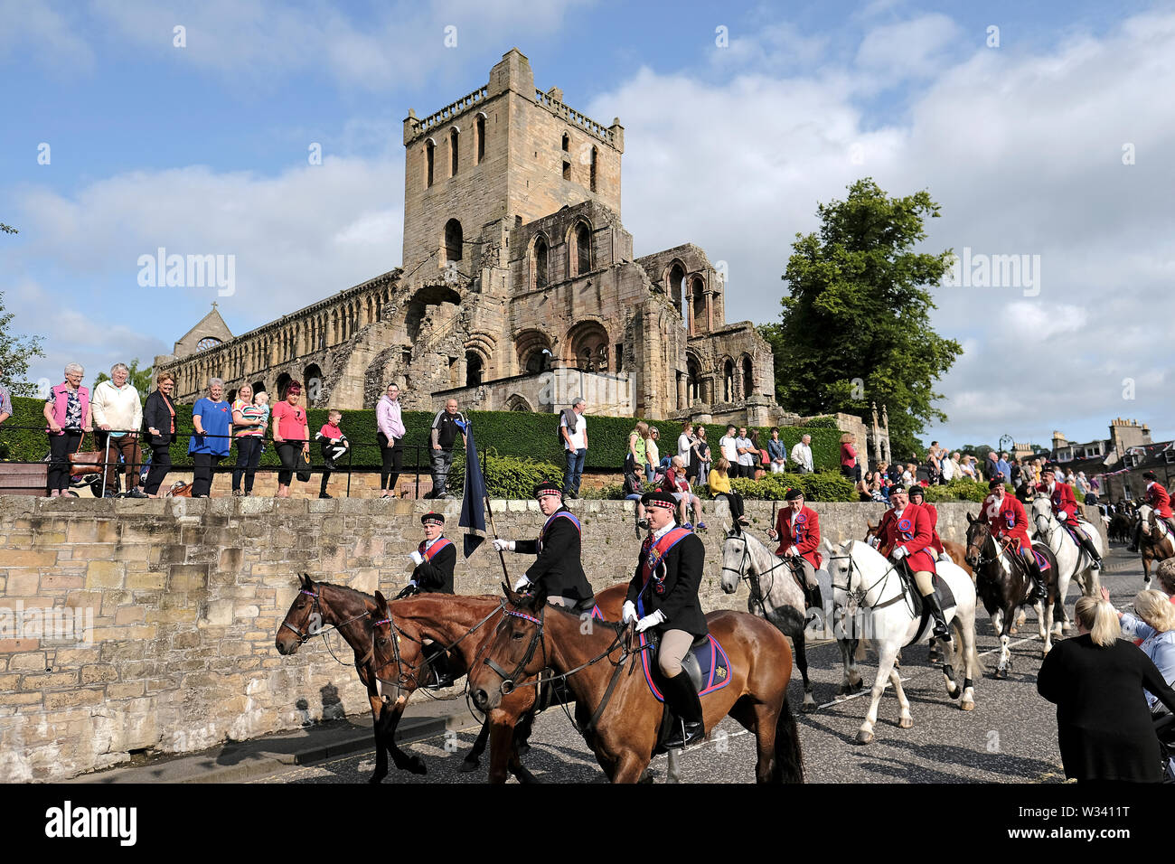 Jedburgh, Scotland, Regno Unito. 12 luglio 2019. Jethart Callant il giorno del Festival 2019 Jethart Callant Euan Munro, passando le rovine di Jedburgh Abbey, mentre a cavallo in Abbey posto, Jedburgh durante il Jethart Callant Festival del giorno, un festival annuale, parte della Scottish comune stagione di equitazione, venerdì 12 luglio 2019, Jedburgh Scottish Borders, Scotland, Regno Unito. Credito: Rob grigio/Alamy Live News Foto Stock