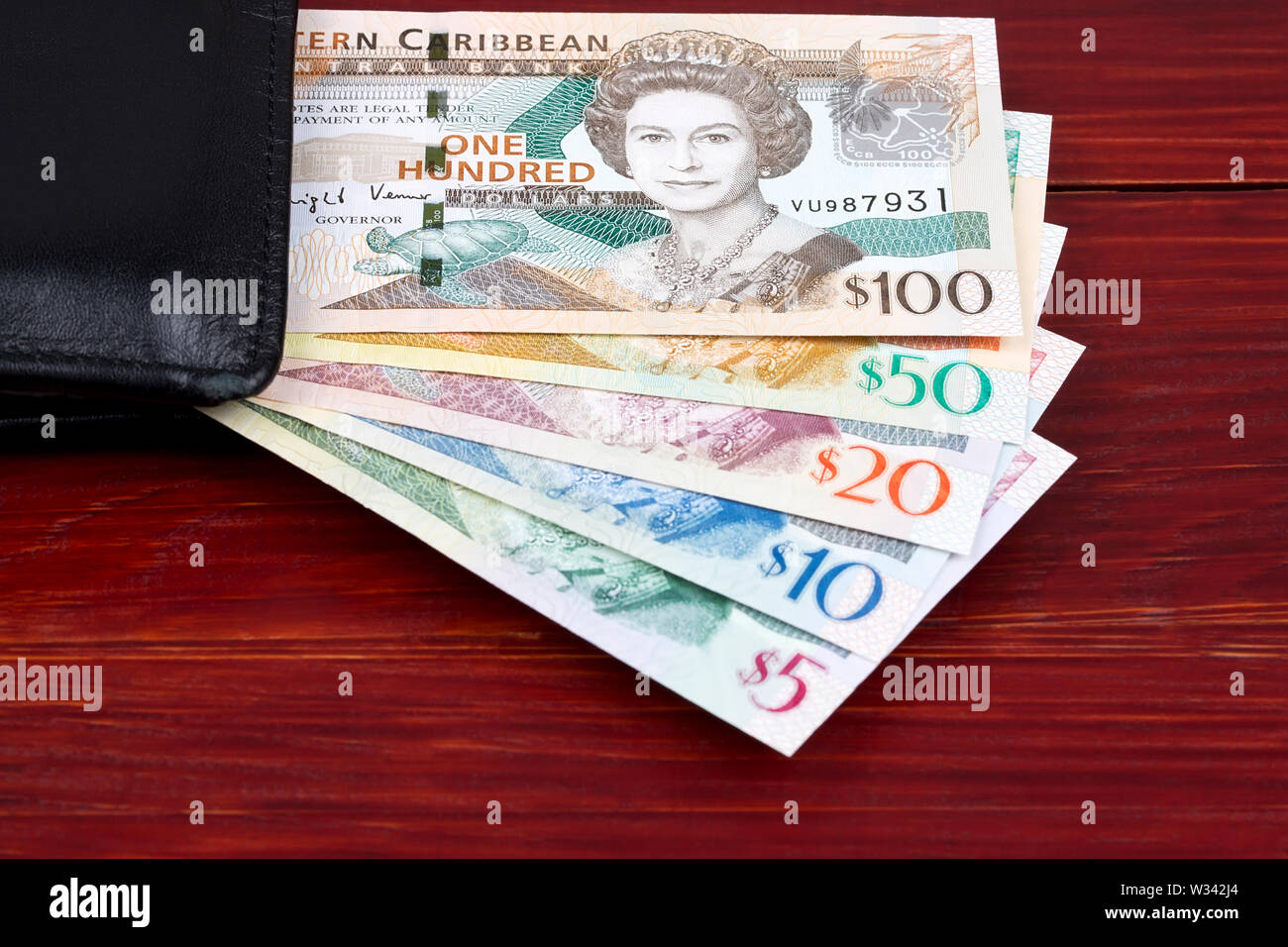 Caraibi Orientali di dollari in un portafoglio di colore nero su uno sfondo di legno Foto Stock