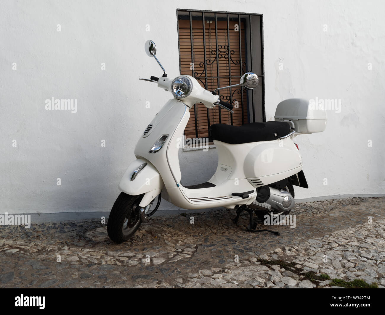 Motor Scooter parcheggiato in una strada acciottolata in Spagna. Foto Stock