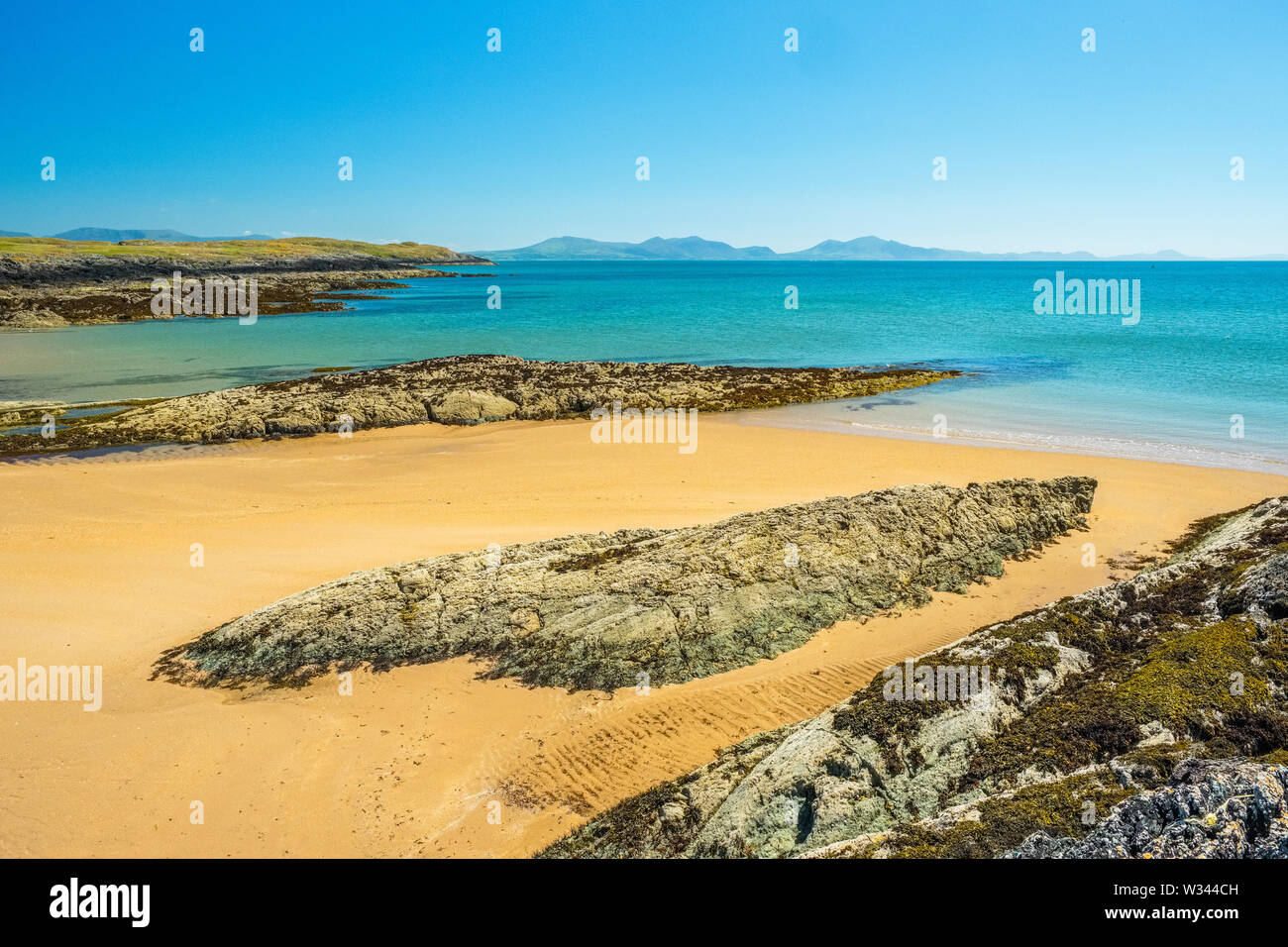 Spiaggia di sabbia sulla costa occidentale di Anglesey con il Lleyn /Llyn Peninsula a distanza Foto Stock