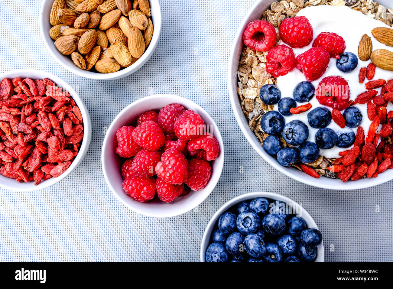 Una sana colazione vegetariana ciotola di muesli con frutta fresca i dadi e yogurt in bianco Bocce Foto Stock